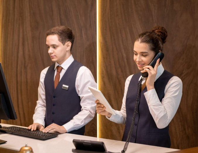 one-of-two-young-hotel-receptionists-looking-at-to-2021-09-24-03-41-39-utc-scaled-e1681390736601